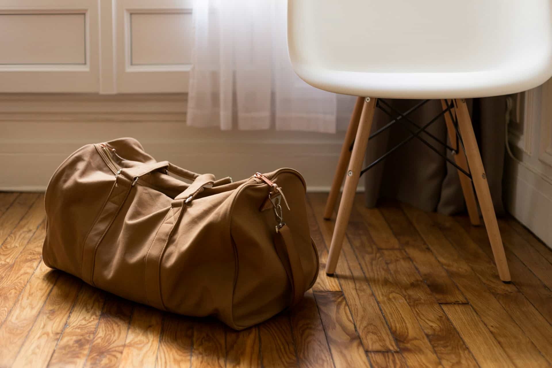 A light brown travel bag on a wooden floor
